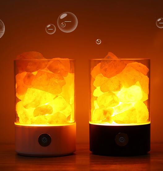 Two illuminated salt lamps with a warm glow on a wooden surface.