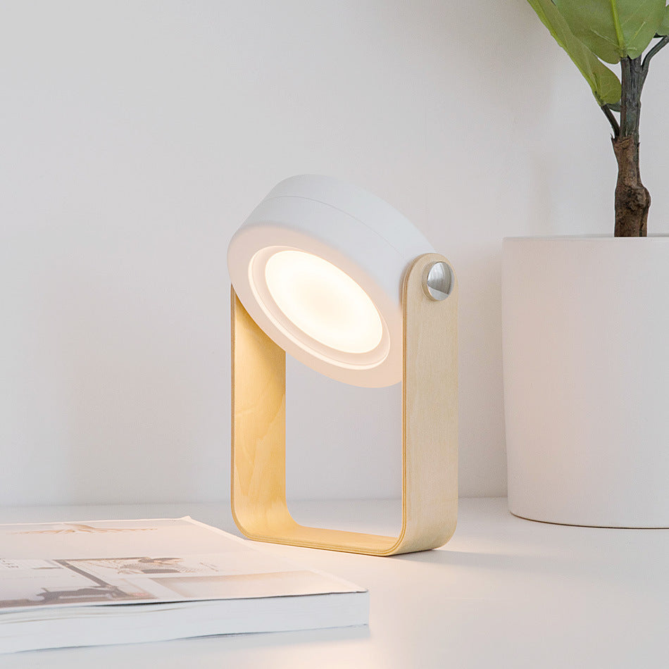 Modern table lamp with a white and gold design on a surface next to a plant