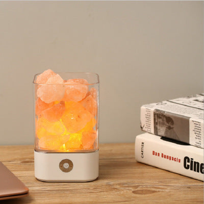 Himalayan salt lamp emitting a warm glow on a wooden surface with books in the background.