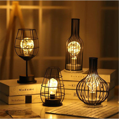 Decorative lamps with wire cages on books against a blurred background