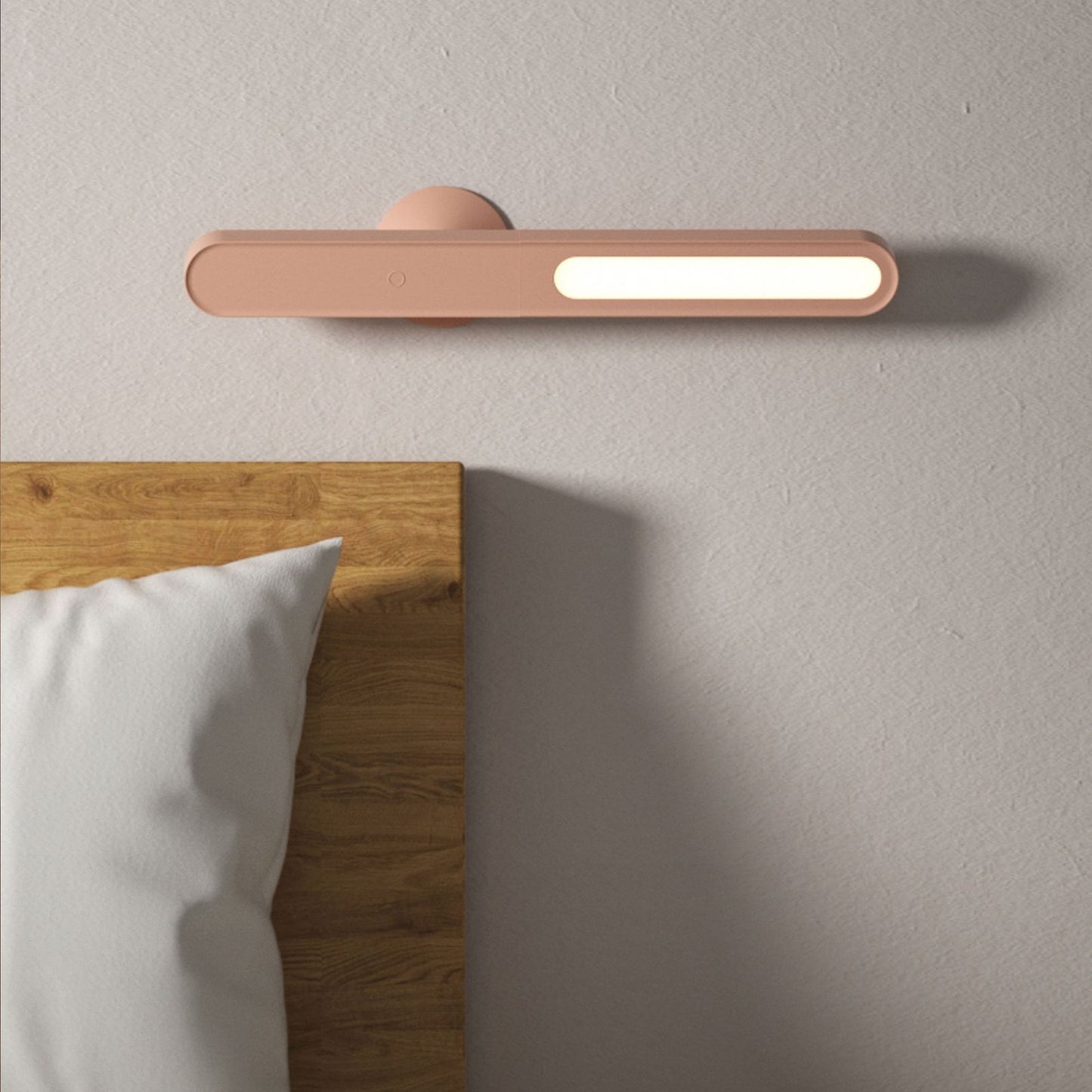 Modern wall-mounted light fixture on a neutral wall next to a bed with wooden headboard and white pillows.