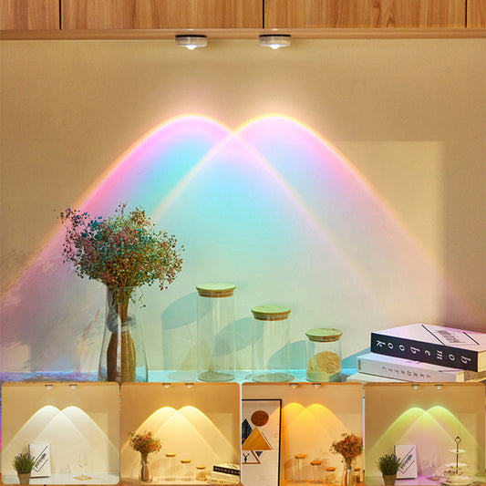 Decorative lights casting rainbow patterns on a wall with books and vases.