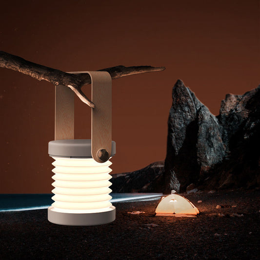 Portable outdoor lanterns hanging from a branch with a natural background
