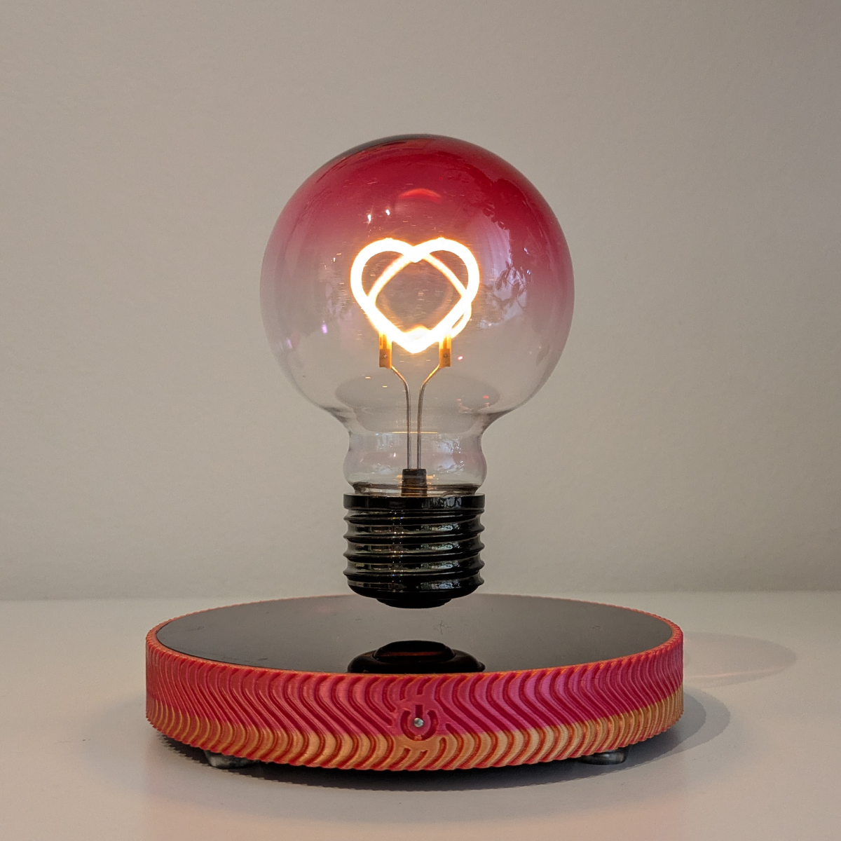 Levitating Heart Shaped Filament Light Bulb Floating Above Glowing LED Base