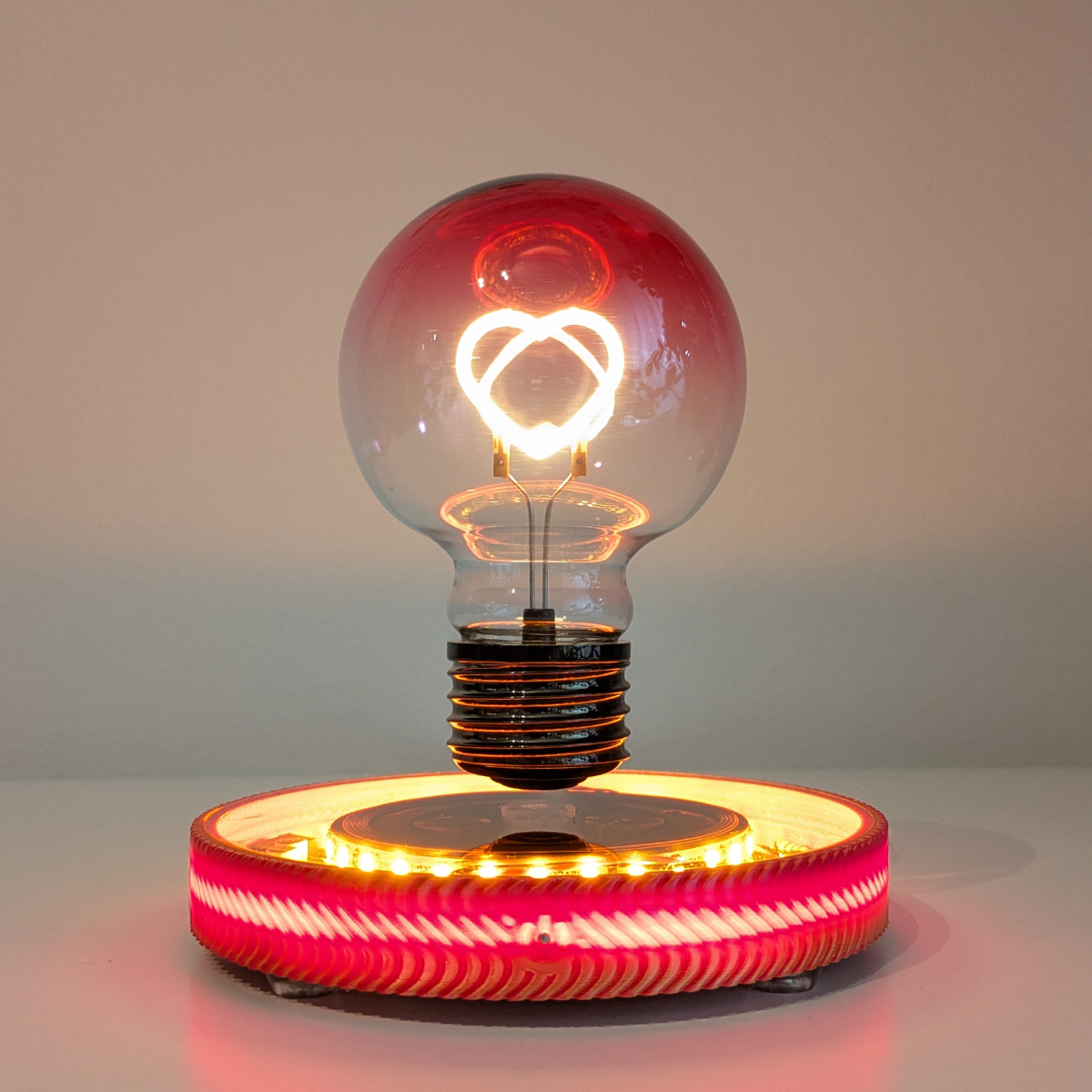 Levitating Heart Shaped Filament Light Bulb Floating Above Glowing LED Base