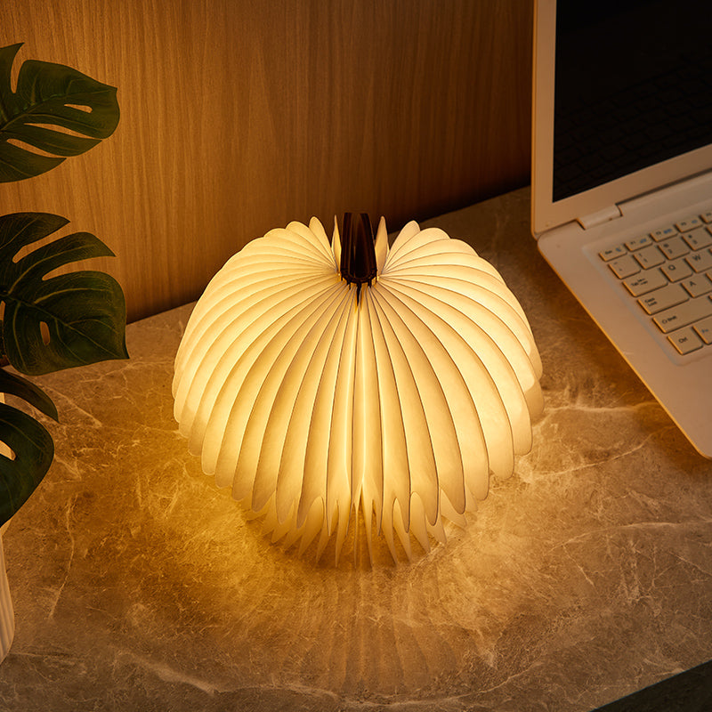 Foldable LED lamp on a desk next to a laptop and plant