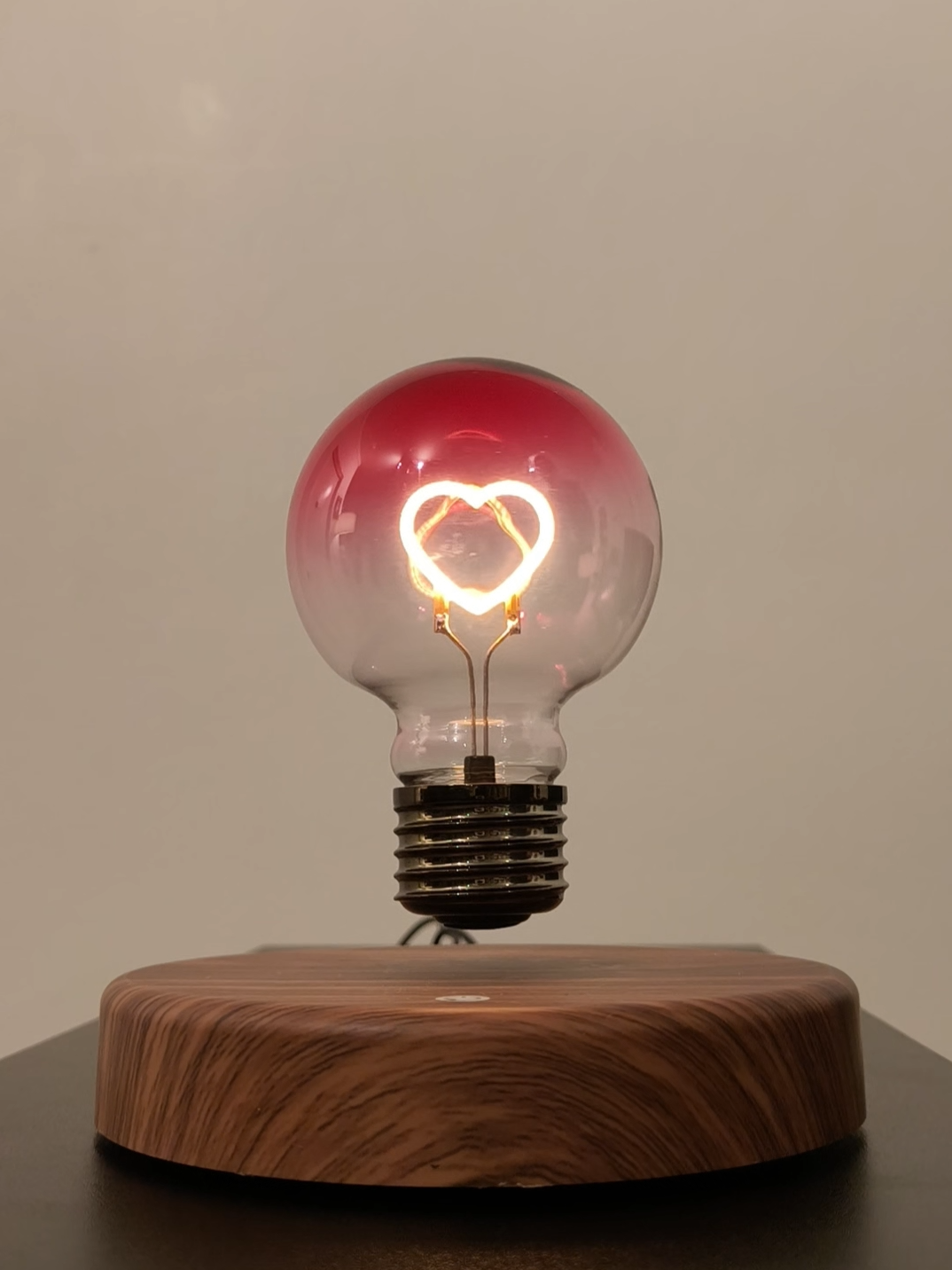 levitating light bulb with pink heart shaped ilament.